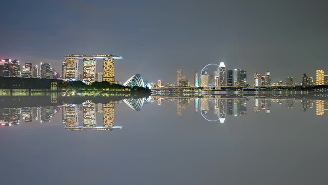 4k time lapse of sunset day to night scene at Marina Bay Singapore city skyline with reflection effect. Zoom out
