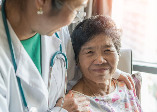 Elderly senior dementia patient (aging old adult person) in nursing hospice home with geriatrician doctor having happy medical health care from hospital carer, caretake or caregiver healthcare service