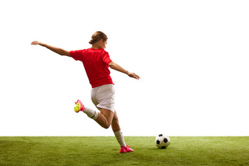 Back view. Young girl, football player in motion, playing on green grass, ready to hit ball isolated on white background. Concept of sport, competition, action, success, motivation. Copy space for ad