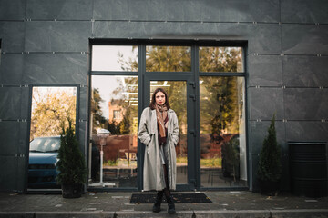 beautiful woman in a gray coat and scarf in the city.