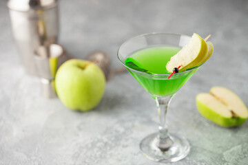 Alcoholic cocktail apple martini or green sour appletini in martini glass . Bar tools.