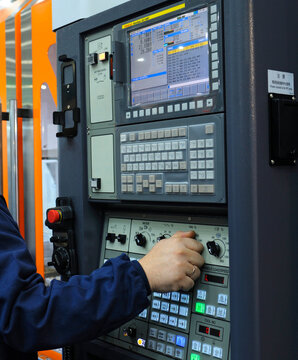 Worker hand turning the switch button on the board of computer numerical control of the lathe, made by Fanuc