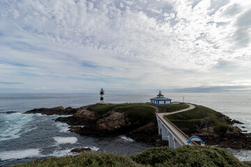 Fototapeta na wymiar Coastal Harmony: Lighthouse and Small Building Adorning a Rocky Coastline