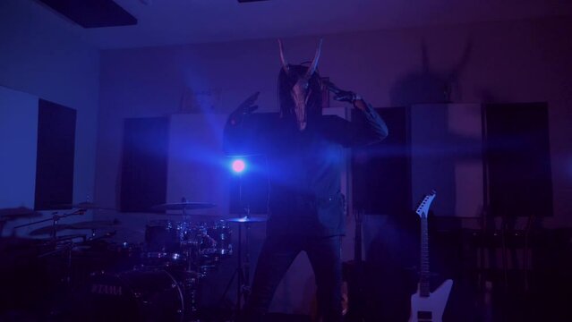 Devil monster suffers, dances, gets angry. A mystical man in a scary mask in a dark studio. Horror, Halloween, Hell