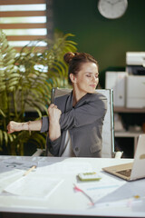 smiling business woman in green office stretching hands