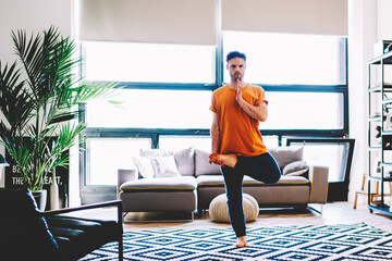 Calm hipster guy standing on one leg enjoying harmony and relaxation