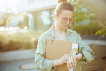 pensive modern woman worker in green blouse and eyeglasses