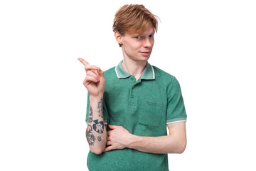 a young smart european guy with red hair with a tattoo on his forearm wears a green t-shirt has an idea and wants to tell it
