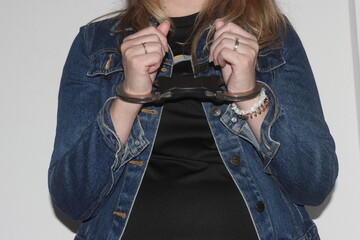 A closeup of the handcuffs on woman who has been arrested for a crime. The prisoner is awaiting...