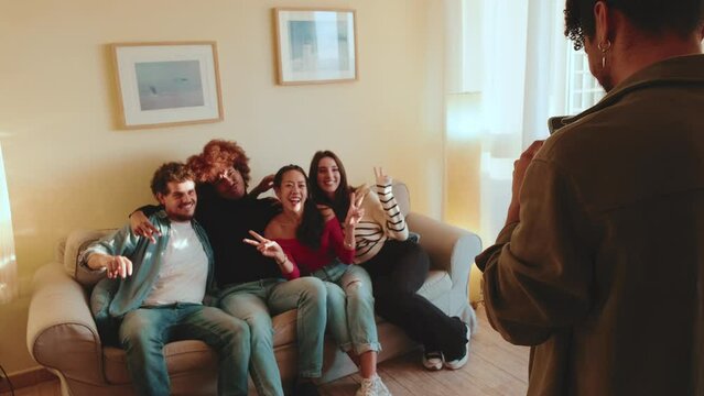 Guy takes pictures of his friends on mobile phone in living room