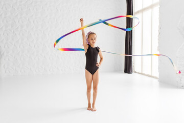 Rhythmic gymnastics. Preteen girl athlete rhythmic gymnastic in black suit does exercise with ribbon