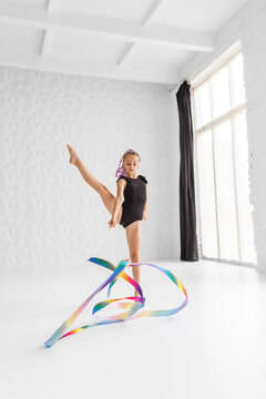 Rhythmic gymnastics. Preteen girl athlete rhythmic gymnastic in black suit does exercise with ribbon