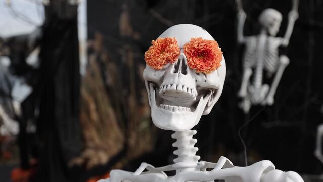 4k clip with human skeleton model with flowers in the eyes at a Halloween fest