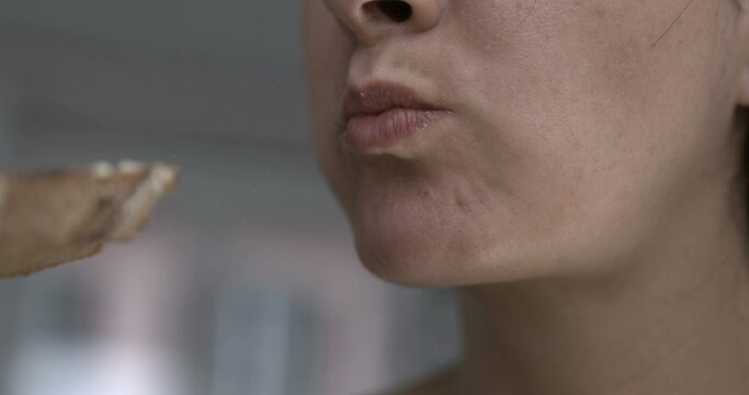 Close-up person mouth chewing food . Woman earing captured with camera
