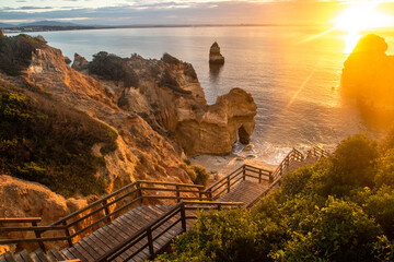 Wooden footbridge to beautiful beach Praia do Camilo near Lagos in Portugal at sunrise - Powered by Adobe