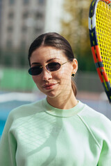 Attractive defiant woman with a racket in her hands poses for the camera on the tennis court.