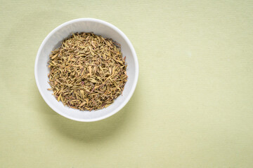 basil dried herb - small ceramic bowl on textured paper with a copy space, top view