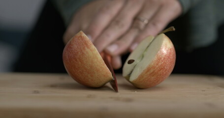 Slicing an apple fuit in half with knife captured in camera