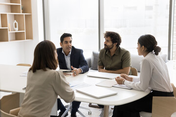 Diverse group of business partners talking at meeting table, discussing investment to startup, project management, teamwork strategy, brainstorming on creative ideas, networking