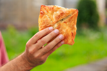 Guy's hand holds puff pastry with cheese, snack and fast food concept. Selective focus on hands...