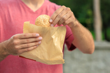 Guy's hand holds mini bread, snack and fast food concept. Selective focus on hands with blurred background