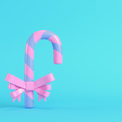 Pink christmas candy cane with a bow  on bright blue background in pastel colors