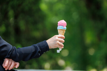 A woman's hand holds ice cream. Selective focus on hands with blurred background