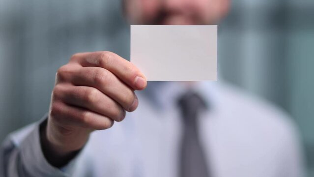 business man holding empty white business card in modern office building. Free blank copy space.