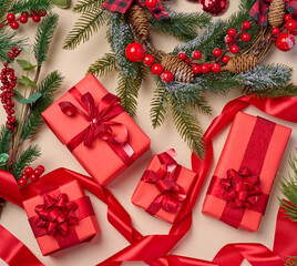 Christmas decor, gifts wrapped in red paper on a beige background, top view