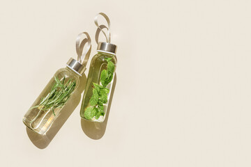 Water drink detox with green rosemary leaves in glass bottle at sunlight on beige background....