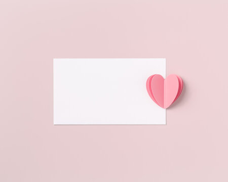 Pink paper heart and empty white paper card for love note on pink colored background. Minimal style flat lay, pastel color, mock up valentine card or wedding invitation. Romantic concept