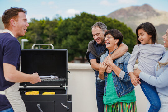 Happy Multi Generational Family Having Fun Cooking Healthy Barbecue Dinner At House Terrace - Grandparents, Parents And Child Outdoor