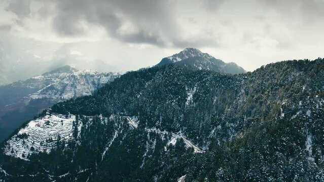 Aerial view of beautiful snow-covered mountains during winters in the Himalayan region of Uttarakhand. Trees and hills are covered in snow. Snowfall in Dhanaulti. Snowcapped forest valley in India. 4K