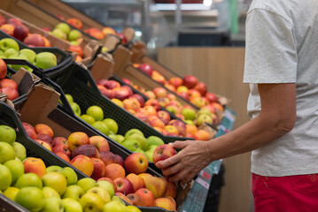 Portrait of senior caucasian woman buying fresh organic vegetables and fruit at market place and holding bag full of healthy food.
