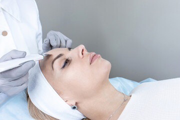 Obraz na płótnie Canvas A dermatologist does an ultrasound facial peeling for a beautiful woman.