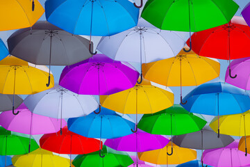 A row of colorful umbrellas suspended above the street. Vibrant urban landscape