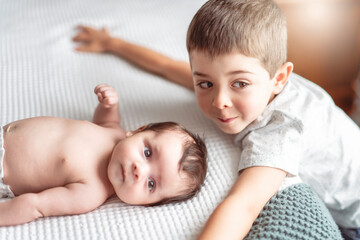 newborn baby in bedroom lying on white sheet with his brother