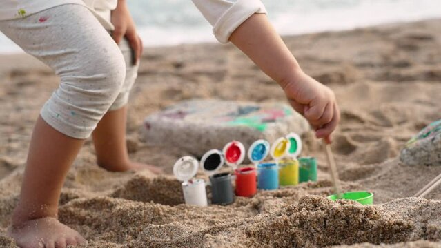Little girl is painting on sand beach. Play and learn actitvities