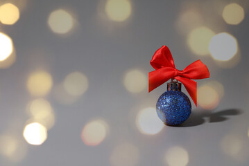 on a gray background - a blue shiny New Year's ball with a red bow. bokeh