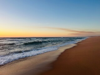 Fototapeta na wymiar Orange sea horizon, sandy coastline, evening seascape reflection, pastel colors