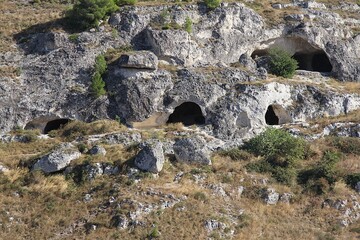 caves carved in the rocks, remains of an ancient city, a hill with carved pits, a rock mountain, Matera, Basilicata, Italy