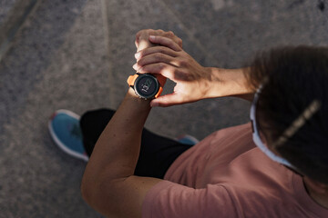 A fitness watch is tested from above, a male athlete looks at the screen and measures the result of a workout in the sports app.