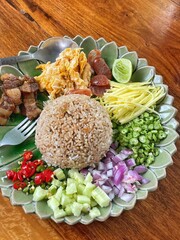 Local Thai food: Rice seasoned with Shrimp Paste and served with dry shrimps, sweet pork, shredded omelette, chopped long beans and sliced green mango