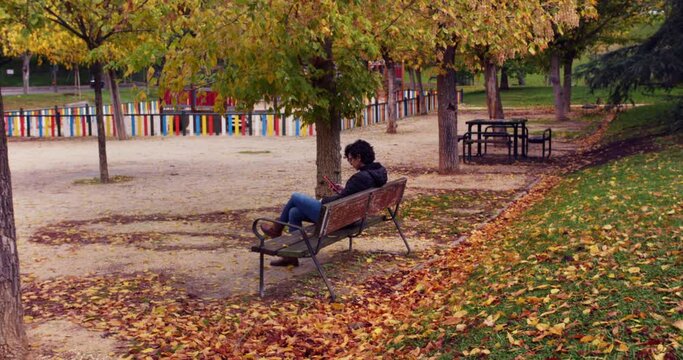 Woman sitting on a bench at a park with her smartphone