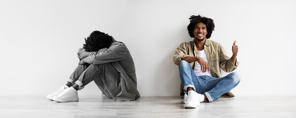 Smiling, unhappy, tired millennial black guy suffer from depression, stress sit on floor, make...