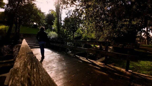 Young woman crossing a bridge at a park