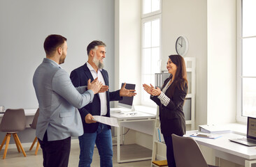 Business people applauding their successful colleague in office. Business team congratulating coworker, expressing gratitude, recognition, appreciation. Good job result, work achievement concept - obrazy, fototapety, plakaty