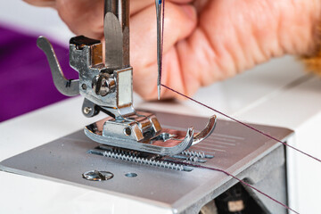 Horizontal photo mature adult woman hands preparing sewing machine. Concept hobbies, handicrafts.