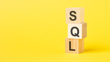 wooden blocks with the text sql - short for structured query language on a bright yellow background