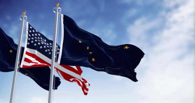 Alaska state flag waving in the wind behind the national flag of the US